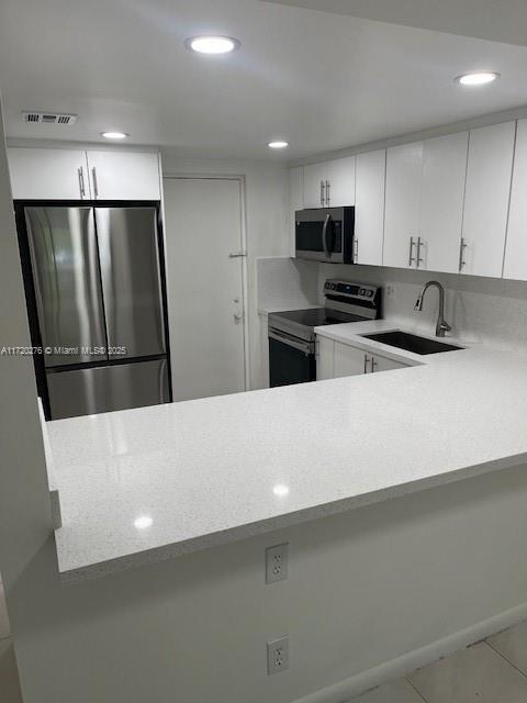 kitchen with light tile patterned flooring, sink, white cabinetry, and stainless steel appliances