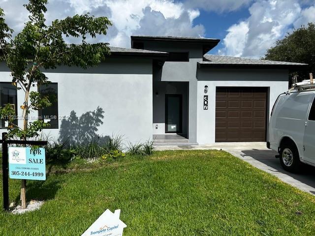 301 NW 28th Ave, Fort Lauderdale, FL 33311 - view of front of home with an attached garage, a front yard, stucco siding, and concrete driveway