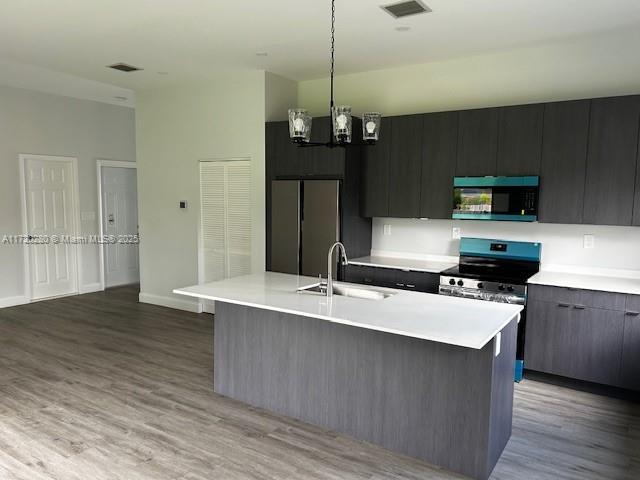 301 NW 28th Ave, Fort Lauderdale, FL 33311 - kitchen with light countertops, wood finished floors, a chandelier, hanging light fixtures, and built in fridge