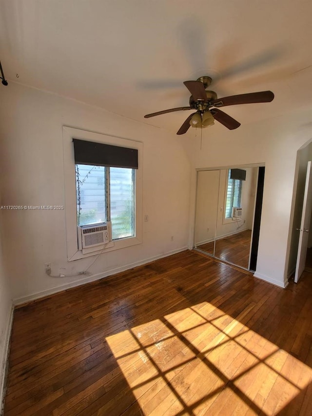 unfurnished bedroom with dark hardwood / wood-style flooring, ceiling fan, a closet, and cooling unit