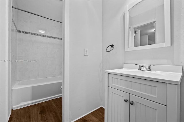 bathroom with hardwood / wood-style floors, vanity, and tiled shower / bath