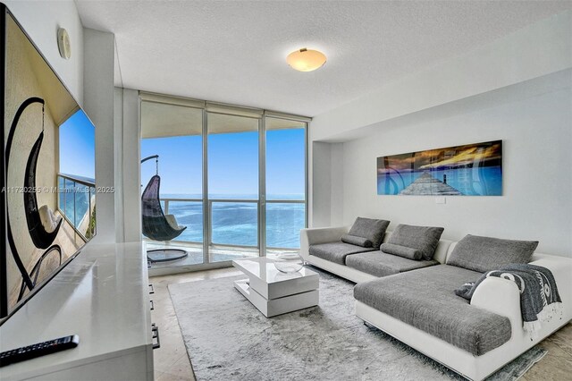 living room with a water view, a wall of windows, and a textured ceiling