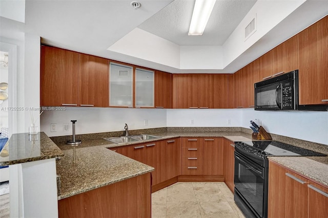 kitchen featuring black appliances, kitchen peninsula, sink, and dark stone counters