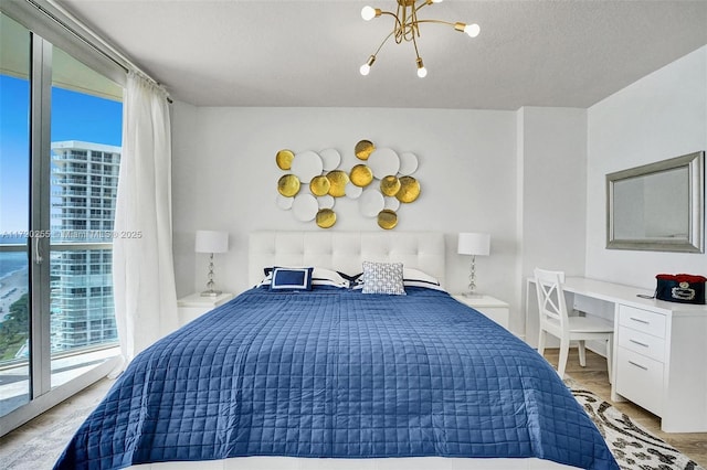 bedroom featuring access to exterior, a notable chandelier, and light wood-type flooring