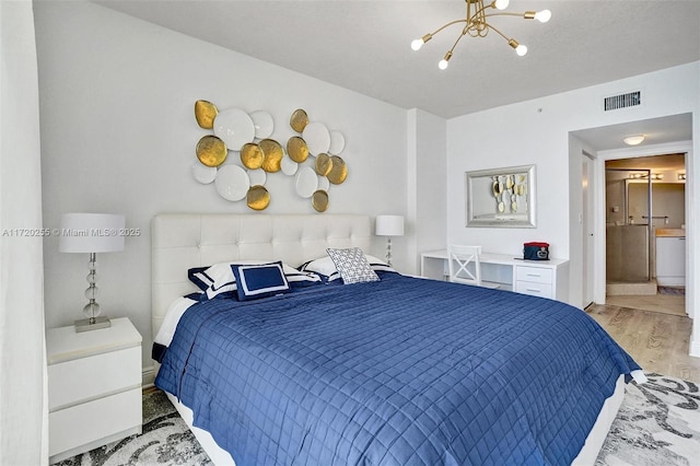 bedroom featuring ensuite bath, hardwood / wood-style floors, and a notable chandelier