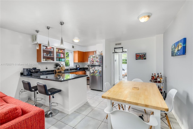 kitchen with kitchen peninsula, stainless steel fridge, light tile patterned floors, and a healthy amount of sunlight