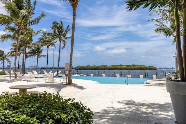 view of swimming pool featuring a water view and a patio area