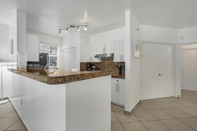 kitchen featuring sink, light tile patterned floors, tasteful backsplash, kitchen peninsula, and white cabinets