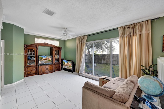 living room with ceiling fan, light tile patterned flooring, and a textured ceiling