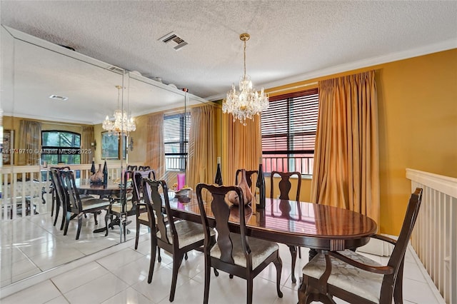 dining area with a textured ceiling, light tile patterned flooring, crown molding, and a chandelier