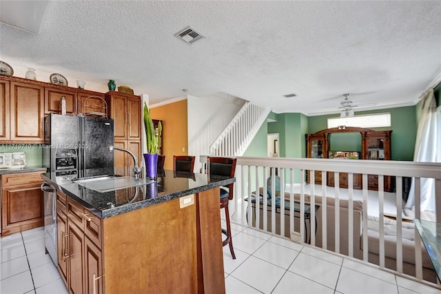 kitchen with light tile patterned floors, ceiling fan, crown molding, and an island with sink