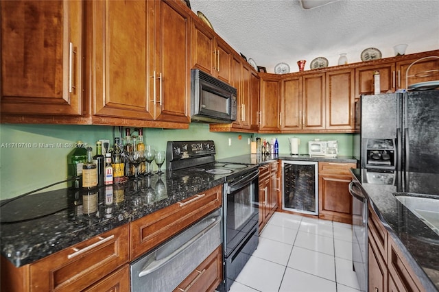 kitchen with dark stone counters, black appliances, light tile patterned floors, a textured ceiling, and beverage cooler