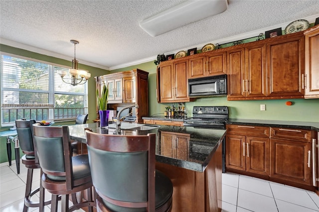 kitchen with light tile patterned flooring, an inviting chandelier, a kitchen island with sink, and black appliances