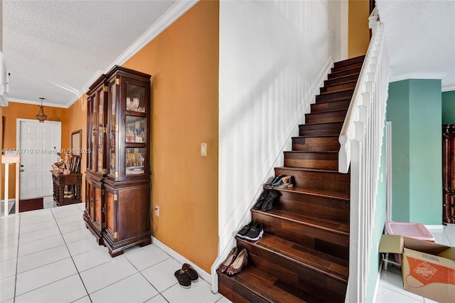 staircase featuring tile patterned floors, crown molding, and a textured ceiling