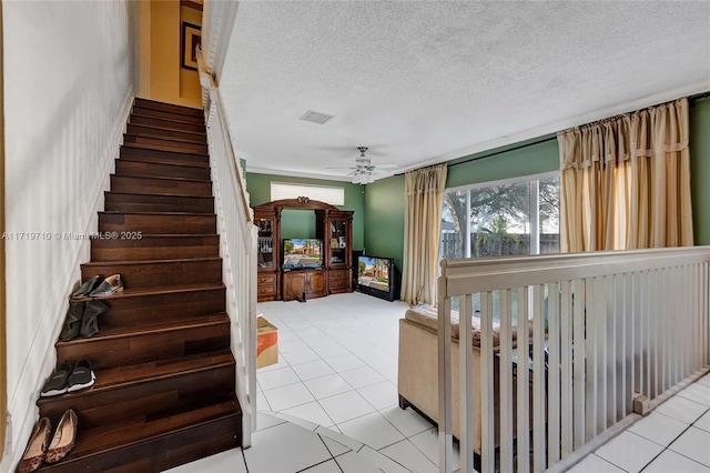 stairway with tile patterned floors, ceiling fan, and a textured ceiling