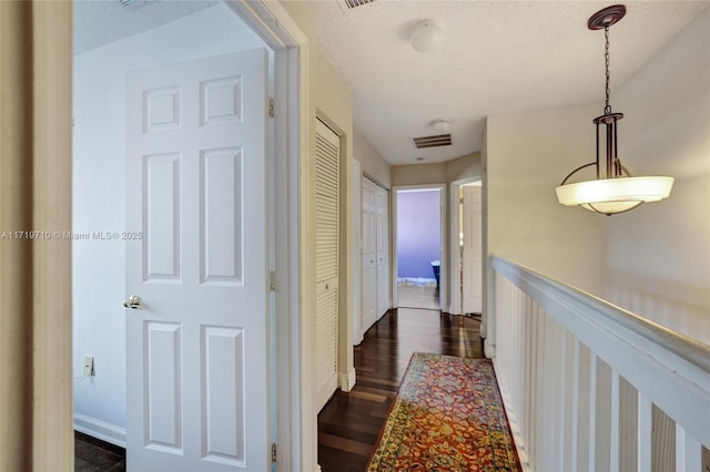 corridor featuring dark hardwood / wood-style flooring and a textured ceiling