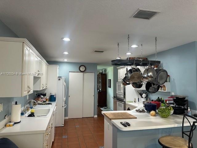 kitchen with sink, kitchen peninsula, oven, a breakfast bar area, and dark tile patterned flooring