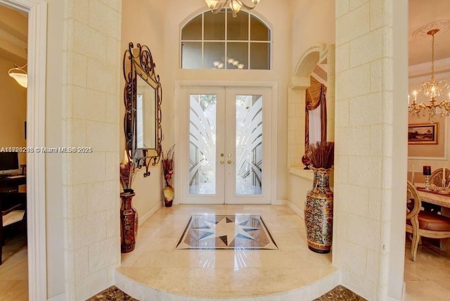 entryway with french doors, a chandelier, and ornamental molding