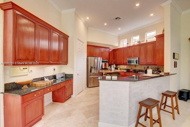 6139 Via Venetia S, Delray Beach, FL 33484 - kitchen with stainless steel appliances, ornamental molding, a peninsula, a kitchen bar, and tasteful backsplash