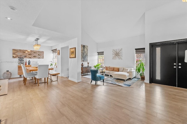 living room with high vaulted ceiling and light hardwood / wood-style flooring