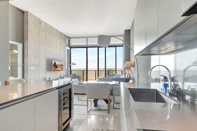 kitchen featuring white cabinets, sink, wine cooler, light tile patterned flooring, and a wall of windows