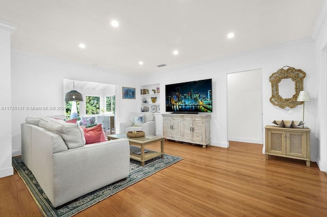 living room featuring built in features, light hardwood / wood-style floors, and ornamental molding