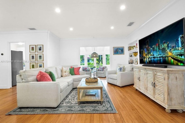 living room featuring built in shelves, light hardwood / wood-style floors, and ornamental molding