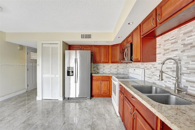 kitchen featuring appliances with stainless steel finishes, tasteful backsplash, light stone counters, a textured ceiling, and sink