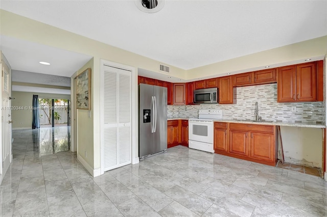 kitchen featuring tasteful backsplash, light stone countertops, sink, and appliances with stainless steel finishes