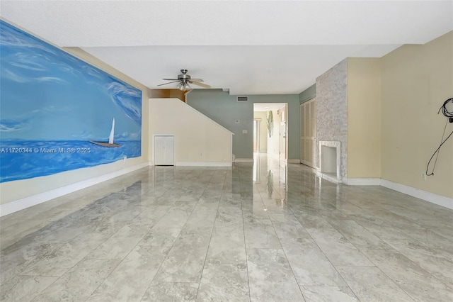 unfurnished room with ceiling fan and a fireplace