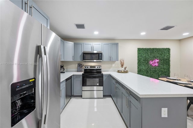 kitchen featuring gray cabinets, kitchen peninsula, and stainless steel appliances