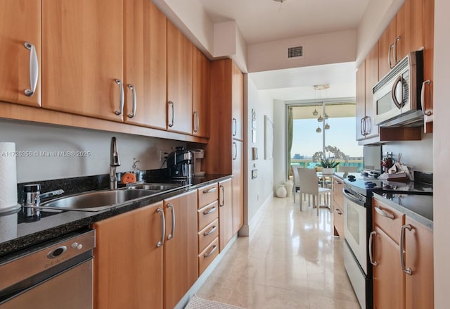 kitchen featuring sink, light tile patterned floors, dark stone counters, and appliances with stainless steel finishes