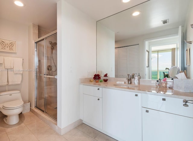 bathroom featuring tile patterned flooring, vanity, toilet, and walk in shower