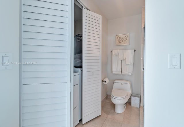 bathroom featuring tile patterned floors, toilet, lofted ceiling, and washer / clothes dryer