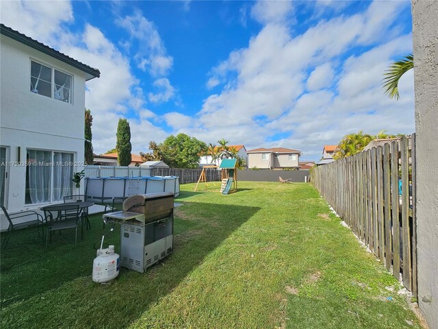 view of yard with a fenced in pool and a playground