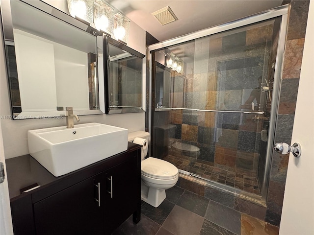 bathroom with a shower with door, vanity, and toilet