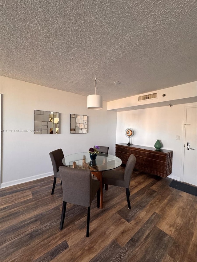 dining space with dark hardwood / wood-style flooring and a textured ceiling