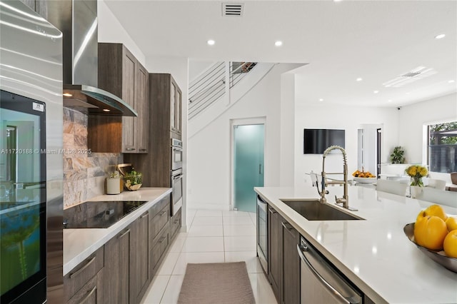 kitchen featuring decorative backsplash, wall chimney exhaust hood, stainless steel appliances, sink, and light tile patterned flooring