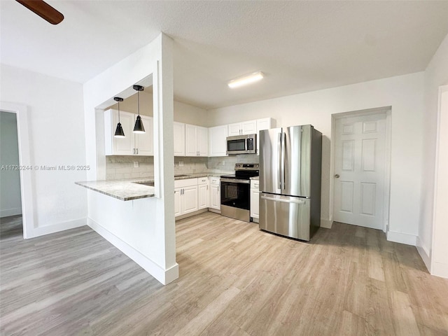 kitchen featuring white cabinetry, kitchen peninsula, appliances with stainless steel finishes, decorative backsplash, and light stone counters