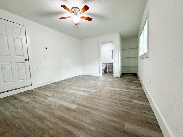 unfurnished bedroom with ensuite bathroom, a textured ceiling, ceiling fan, and light hardwood / wood-style floors