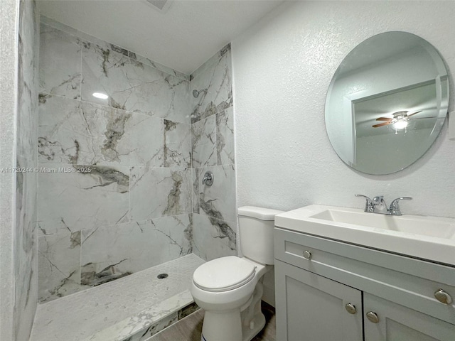 bathroom with vanity, toilet, and a tile shower