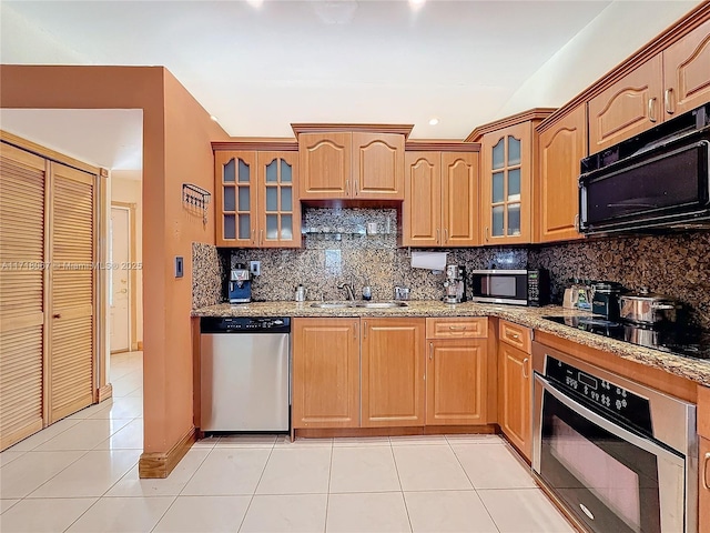 kitchen with tasteful backsplash, light tile patterned floors, sink, and black appliances