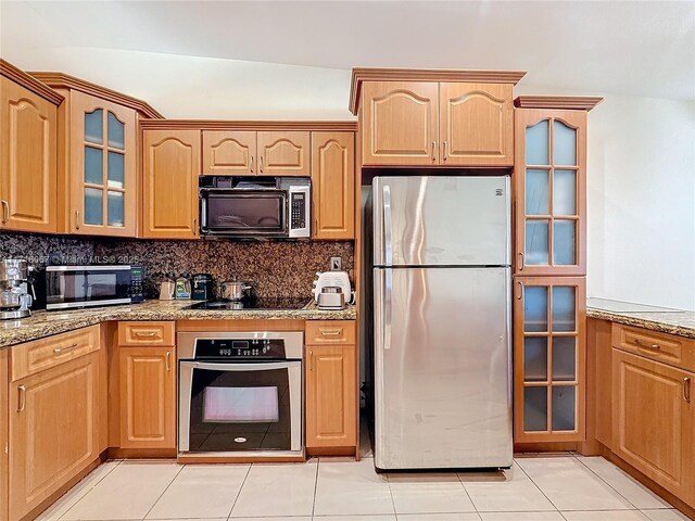 kitchen with appliances with stainless steel finishes, light tile patterned floors, backsplash, and light stone counters