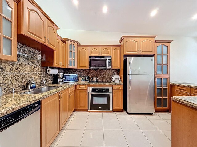 kitchen with sink, decorative backsplash, stainless steel appliances, and light stone countertops