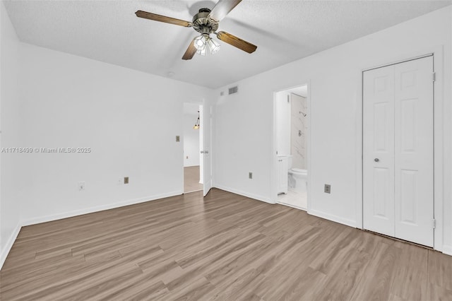 unfurnished bedroom featuring a textured ceiling, ensuite bathroom, ceiling fan, and light hardwood / wood-style floors