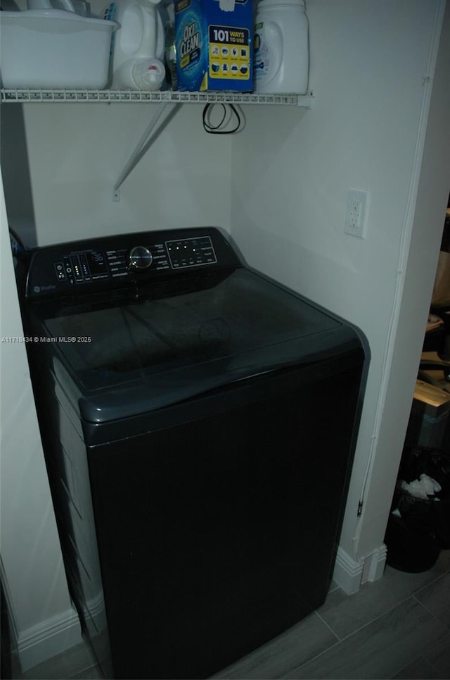 clothes washing area with wood tiled floor, baseboards, separate washer and dryer, and laundry area