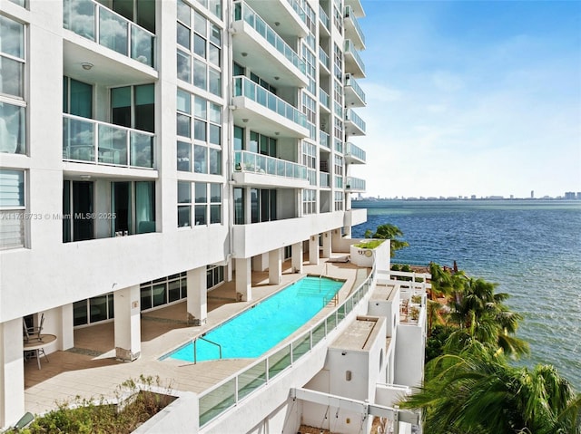 view of swimming pool featuring a patio and a water view