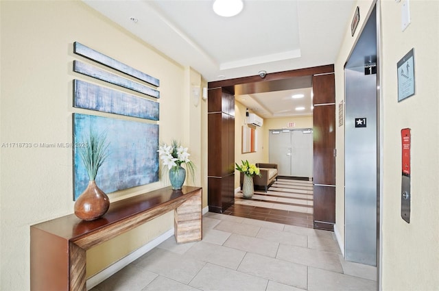 hallway featuring a tray ceiling, elevator, light tile patterned floors, and a wall mounted air conditioner