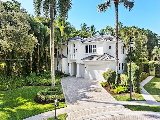 mediterranean / spanish-style home featuring a garage, a balcony, and a front lawn