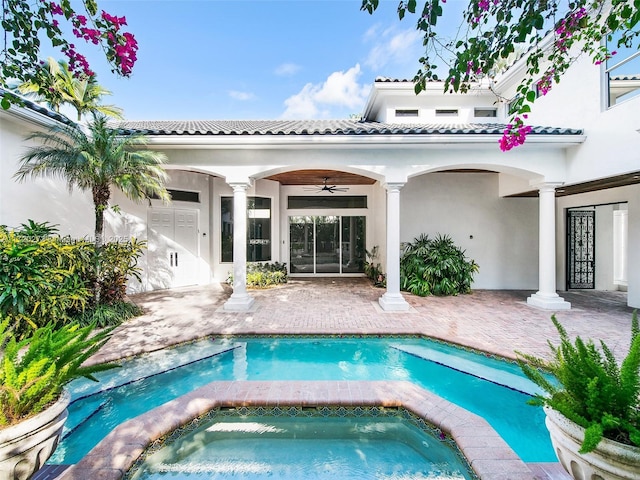 rear view of property featuring ceiling fan, a swimming pool with hot tub, and a patio